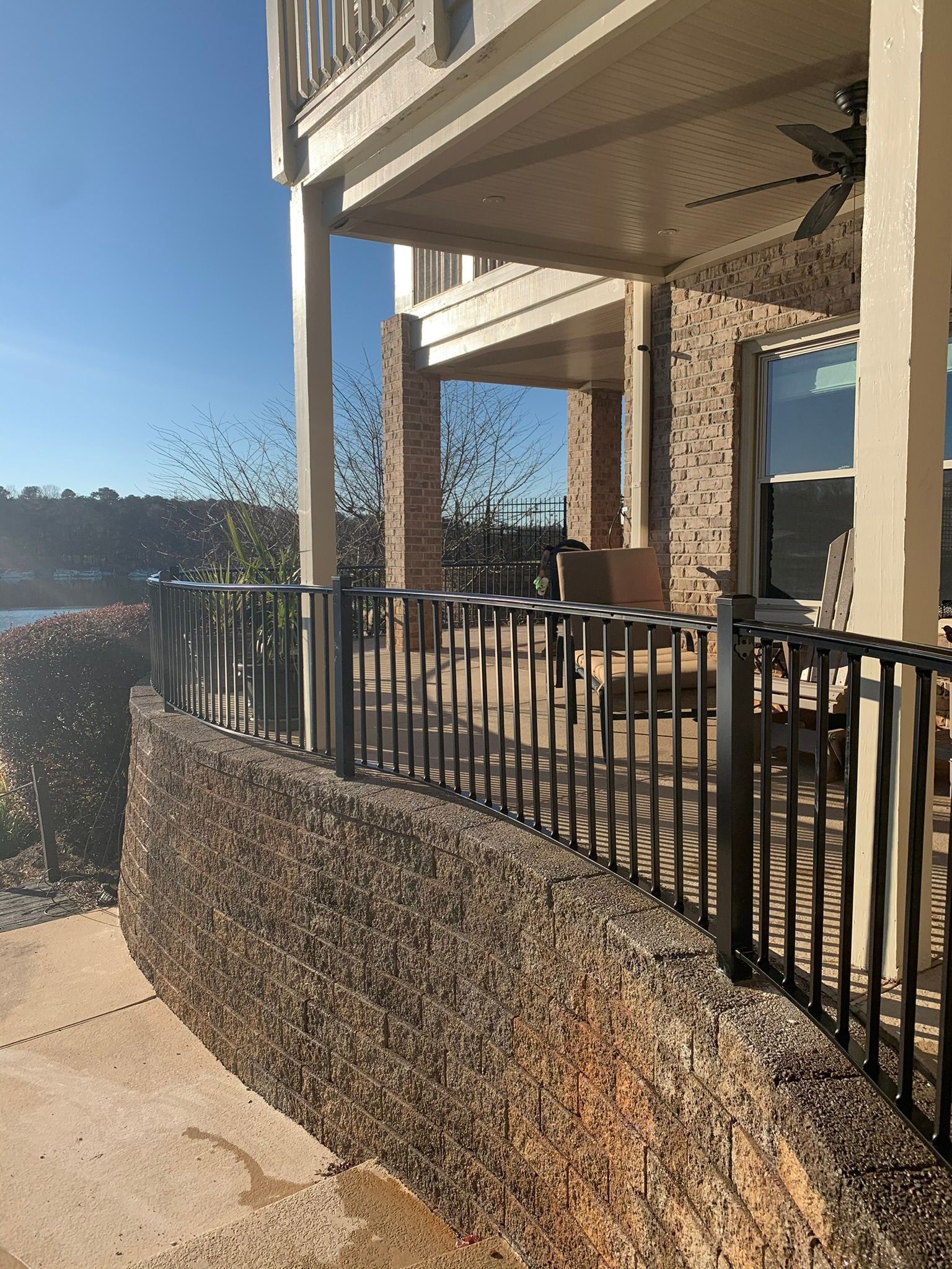 A house with a fence and a balcony overlooking a body of water.