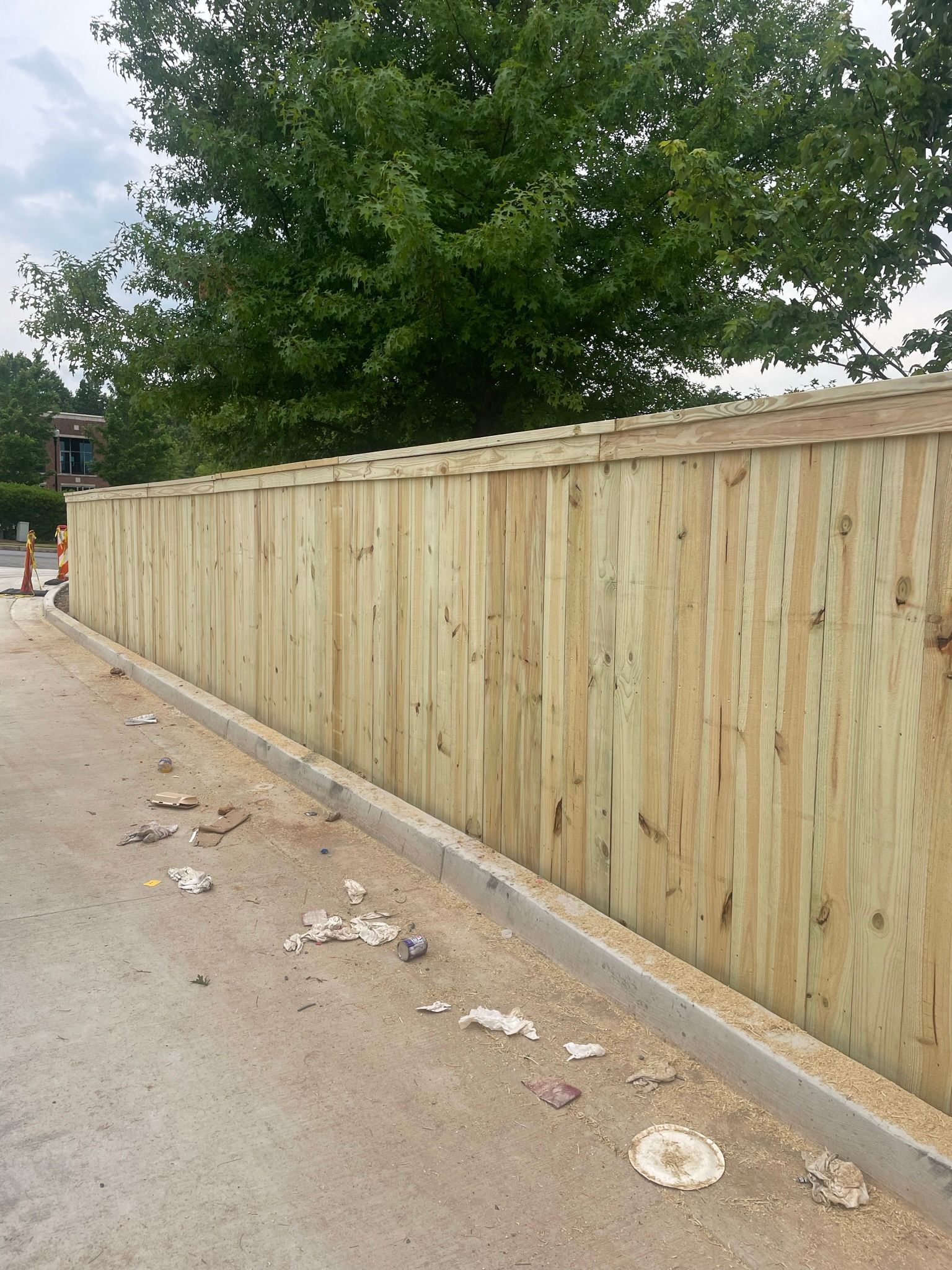 A wooden privacy fence is being built on the side of a road.