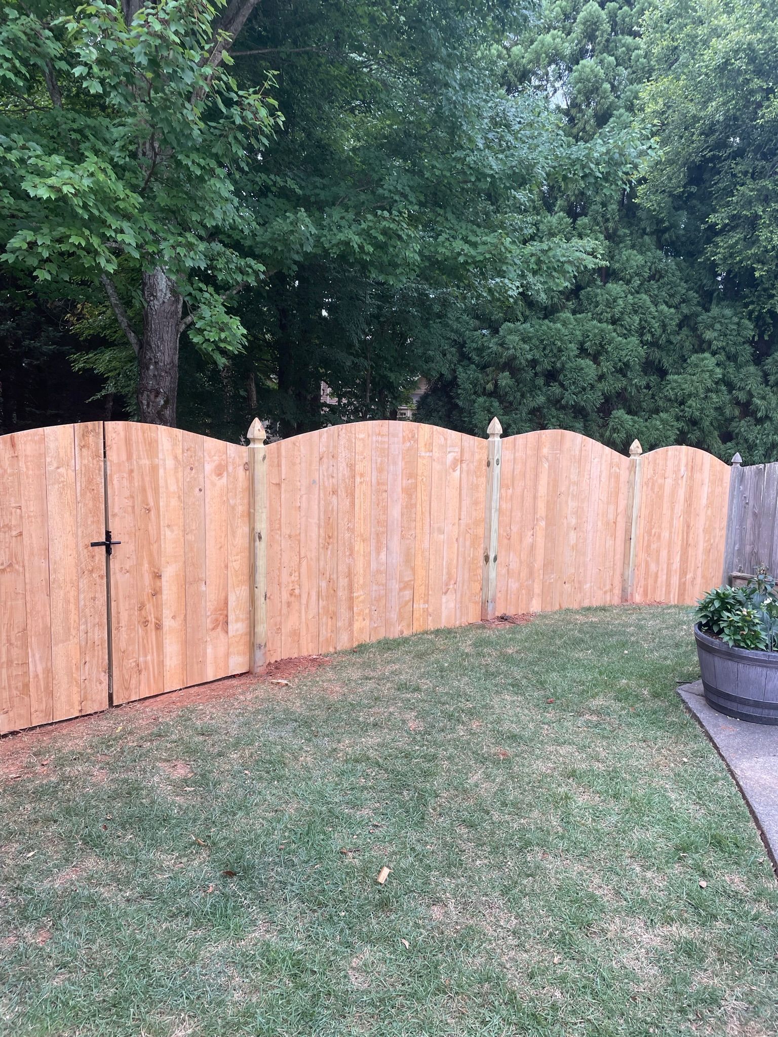 A wooden fence is in the middle of a lush green yard.