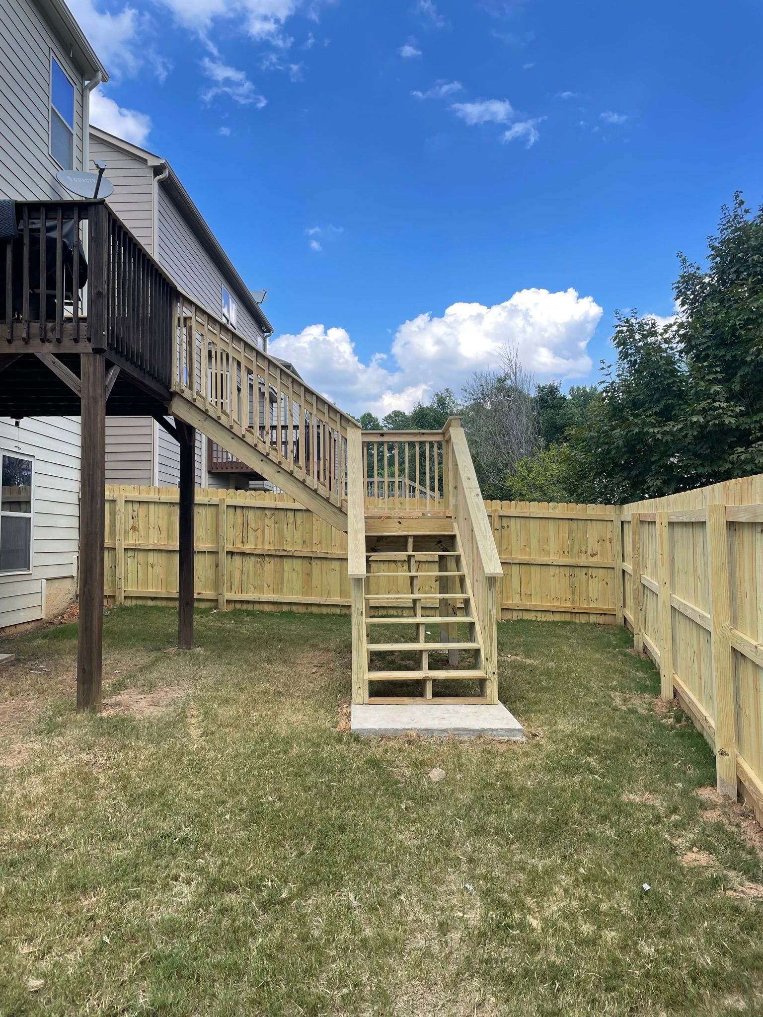 A wooden deck with stairs and a wooden fence in the backyard of a house in North Georgia