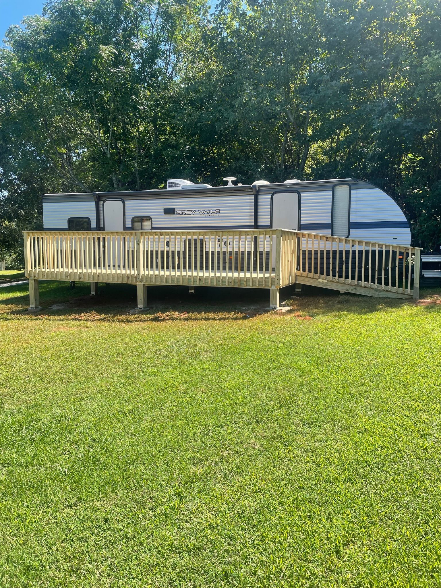A trailer with a wooden deck attached to it is parked in a grassy field in North Georgia