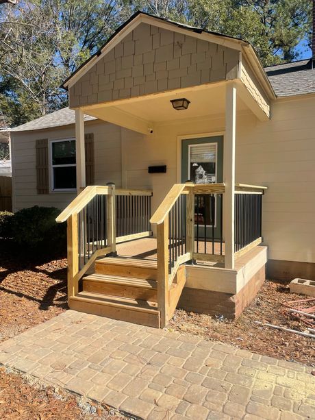 A small house with a porch and stairs in front of it.