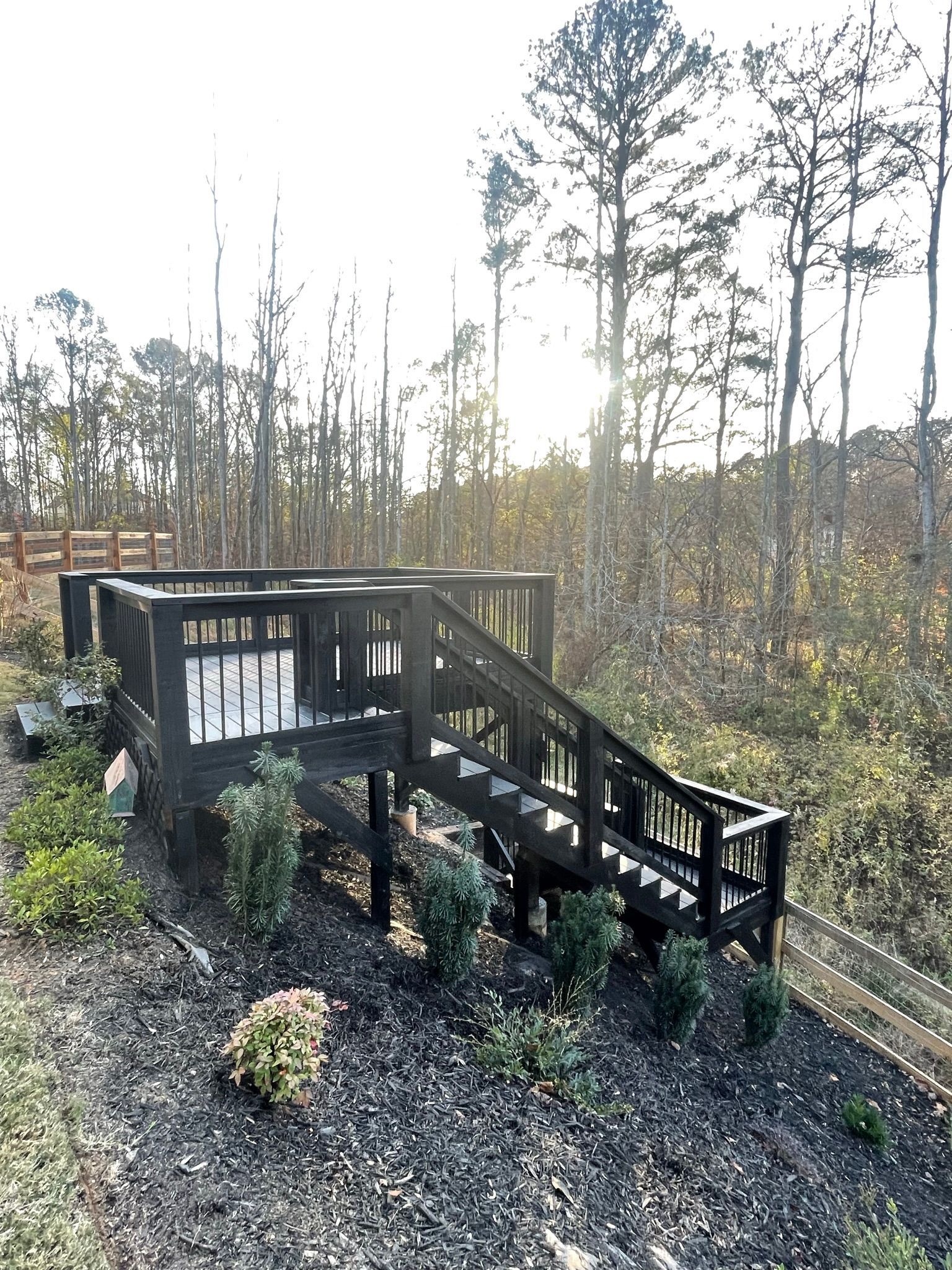 A wooden deck with stairs leading up to it in the middle of a forest in North Georgia