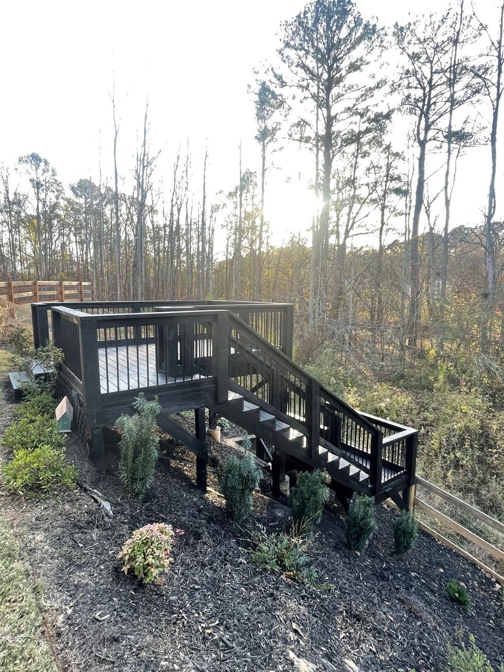A wooden deck with stairs leading up to it in the middle of a forest.