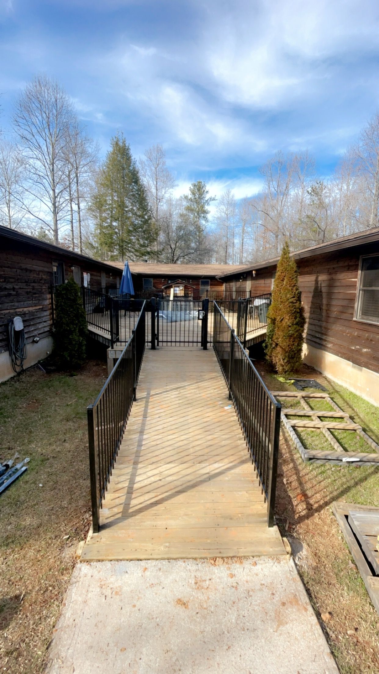 A walkway leading to a swimming pool between two buildings with aluminum railings