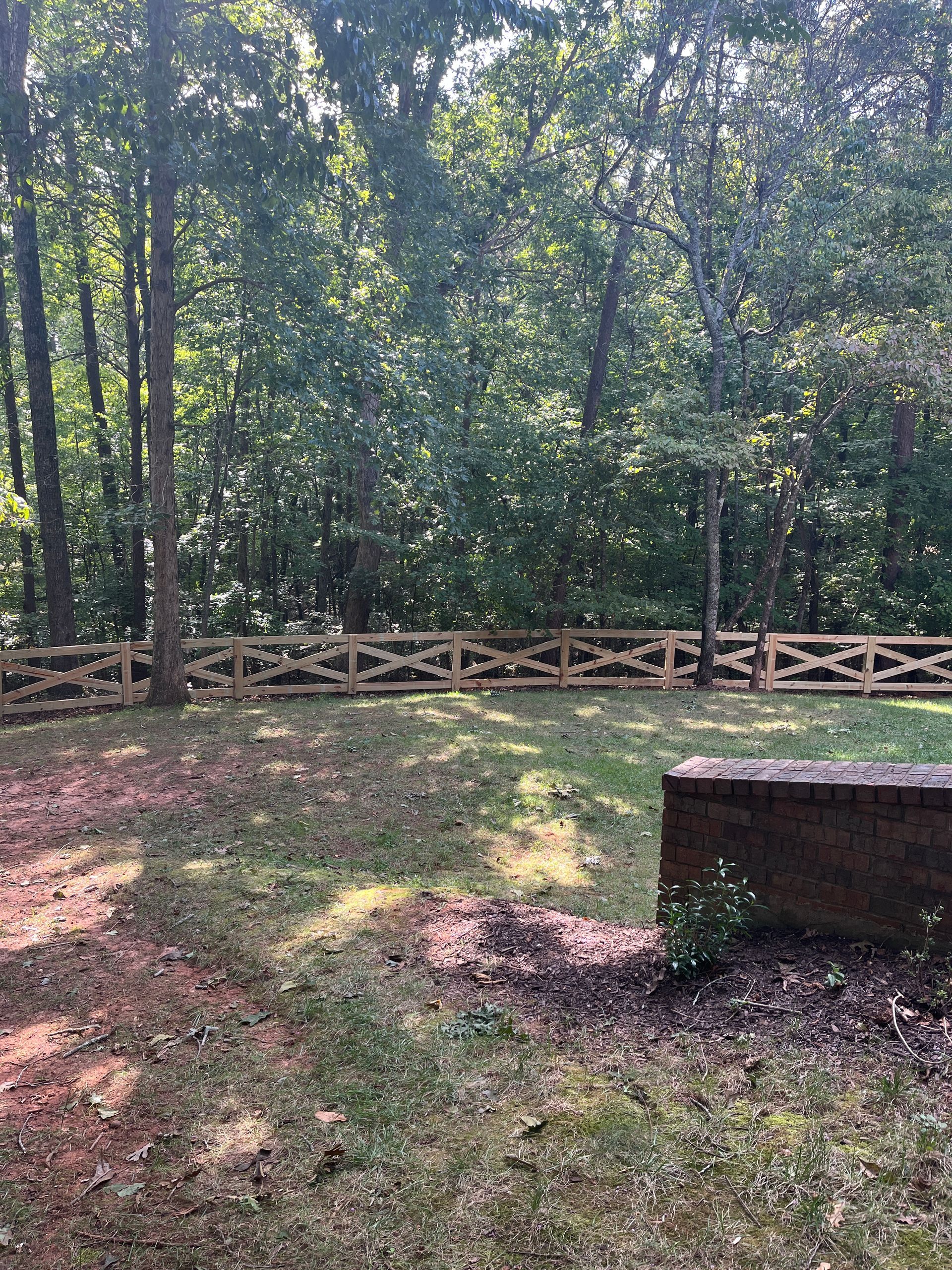 A split rail wooden fence surrounds a grassy area in North Georgia