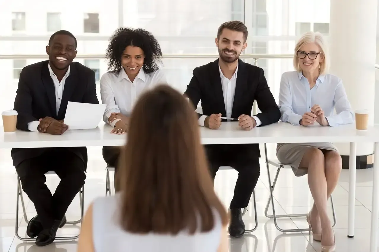 A group of people are sitting at a table having a job interview.