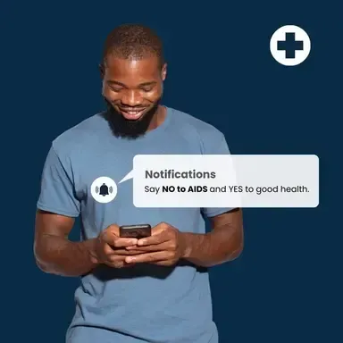 A man in a blue shirt is looking at his cell phone.