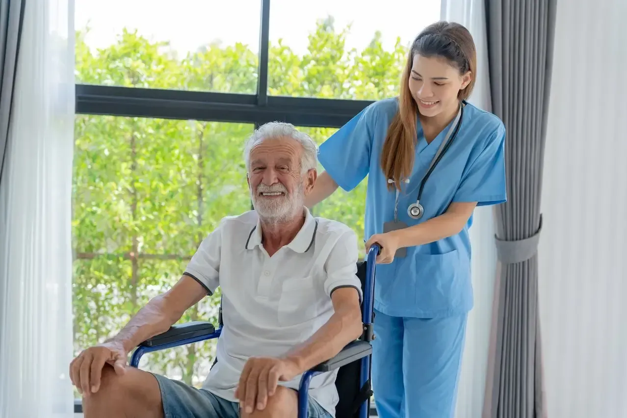 A nurse is helping an elderly man in a wheelchair.