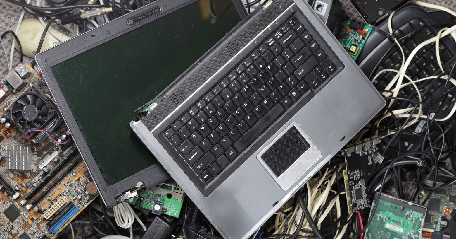 Laptop and electronics waste, including circuit boards, scattered on a surface.
