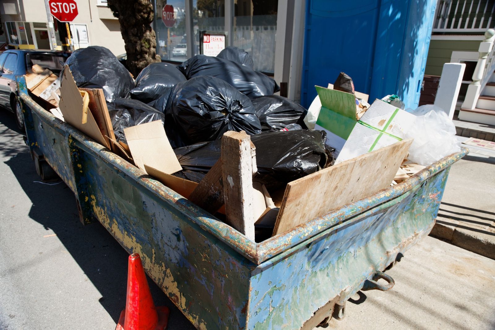 A dumpster filled with garbage is parked on the side of the road.