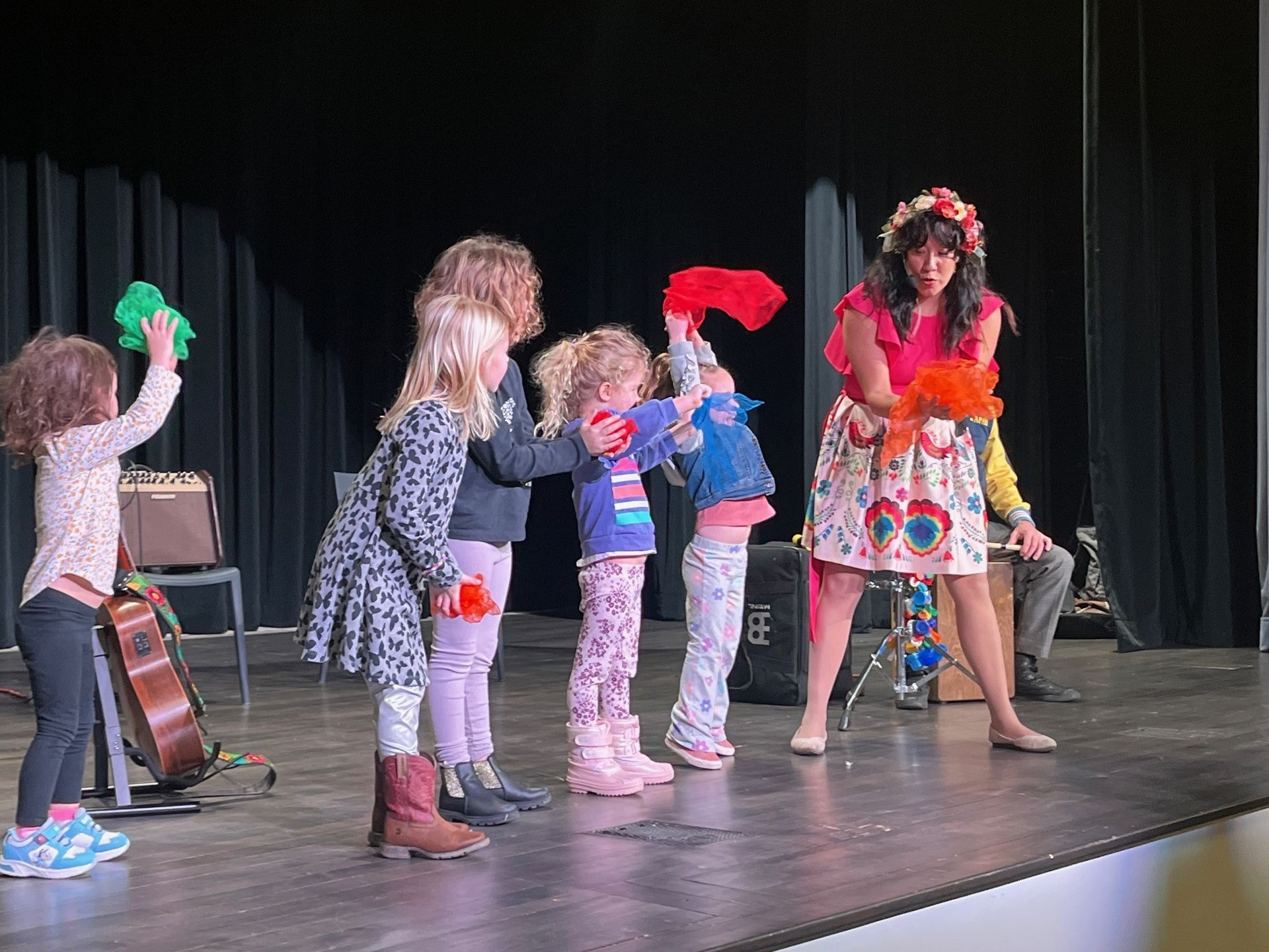 A group of young girls are standing on a stage with a woman.