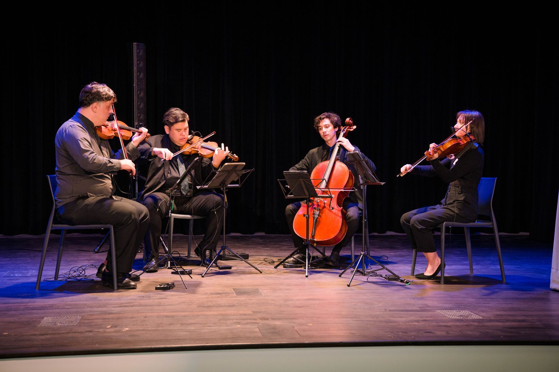 A group of people are playing violins and cello on a stage.