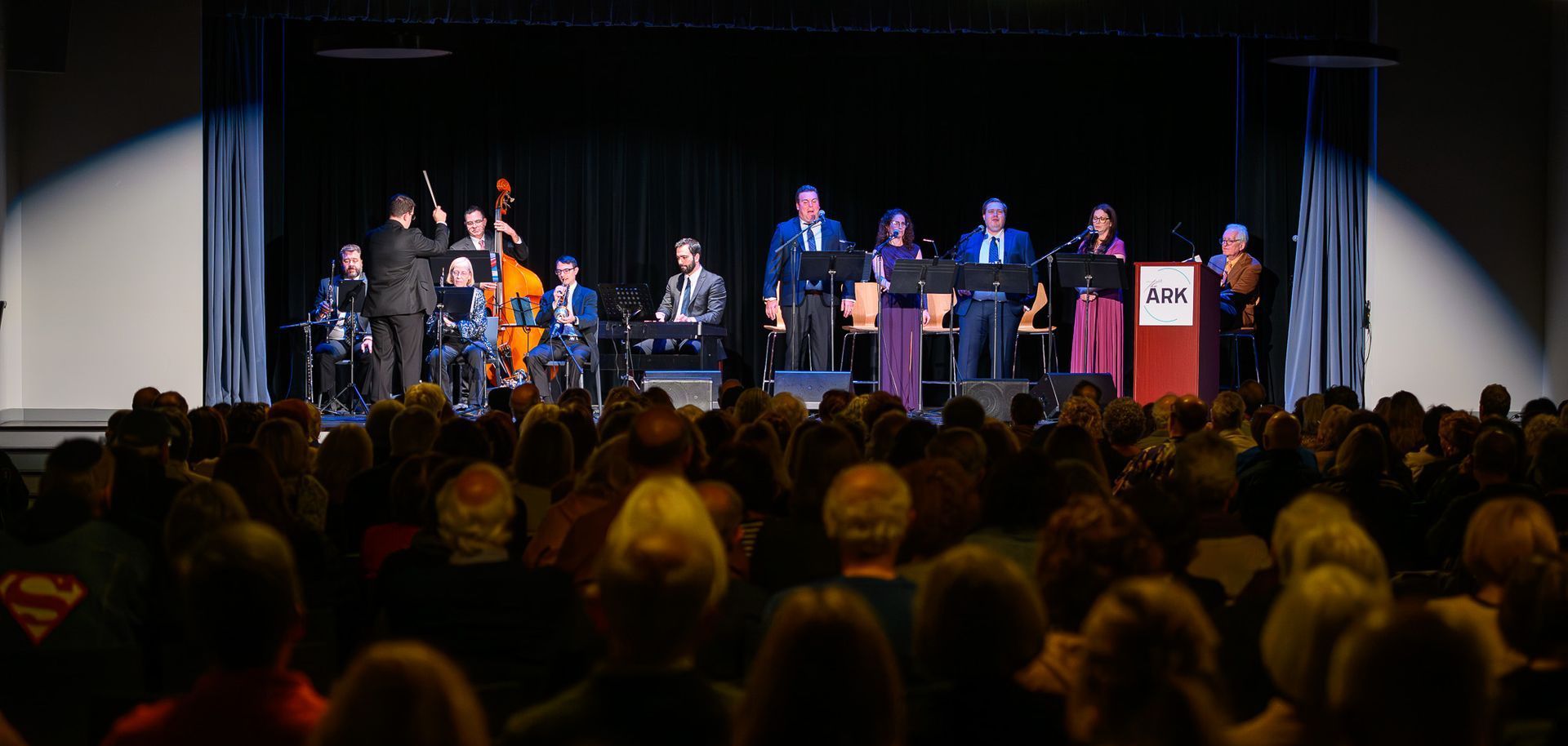 A group of people are standing on a stage in front of a crowd.