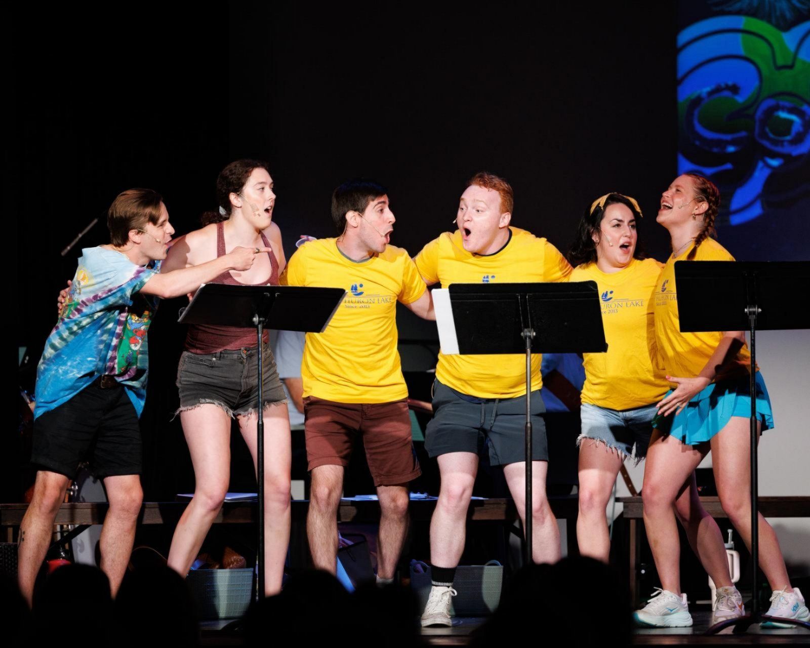 A group of people are standing in front of microphones on a stage.