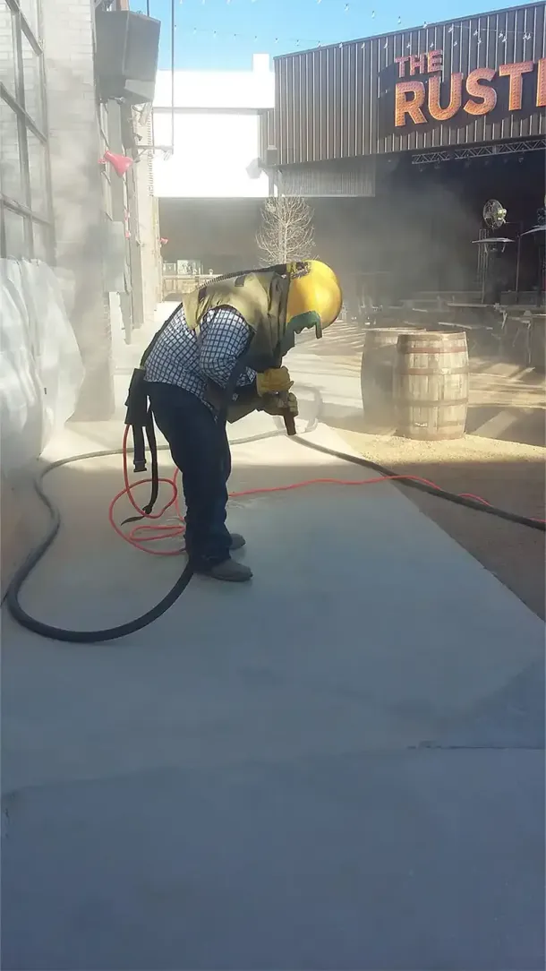 A rooftop pool and hot tub set in a wooden deck overlooking a distant city skyline under a clear blue sky.
