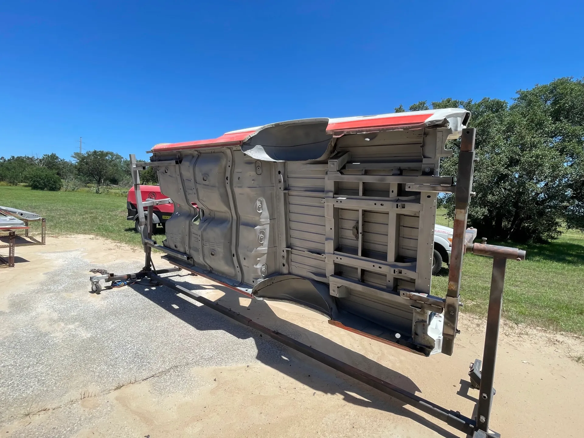 A worker in a yellow safety vest uses a power sprayer to clean the concrete ground in front of a modern glass building.