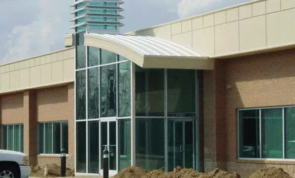 Building entrance with glass doors, curved roof, and brick exterior.