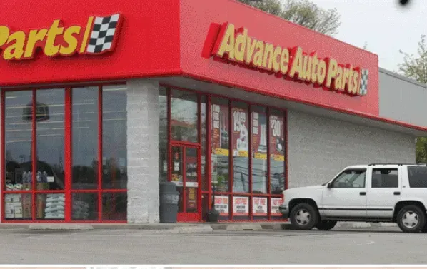 Exterior of an Advance Auto Parts store; red and white signage; white SUV parked outside.