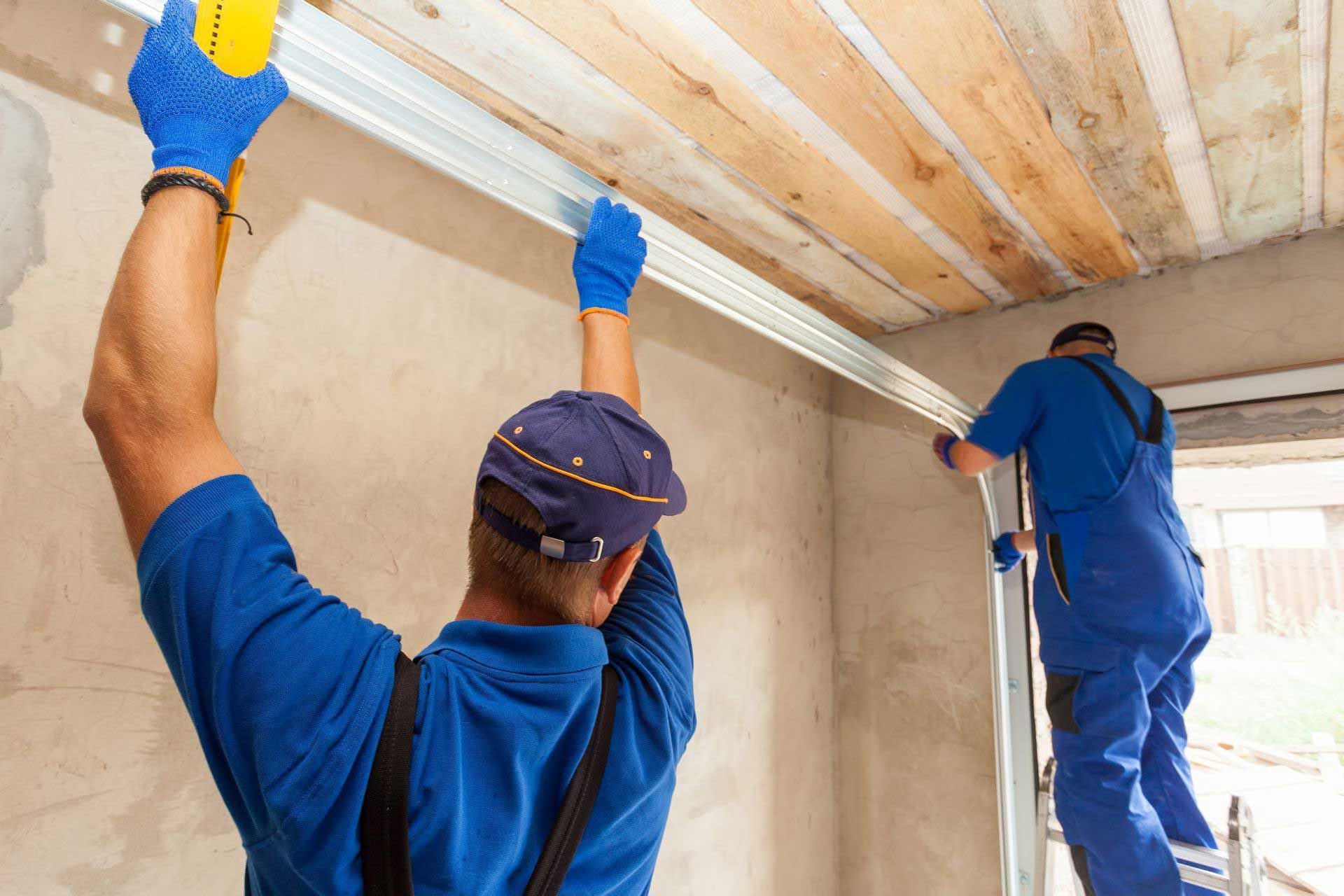 Two workers installing metal track on a wall, next to a wooden ceiling.