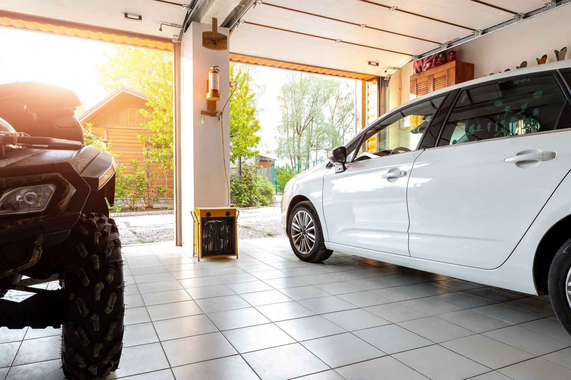 Garage with a white car, ATV, and open garage door. Sunlight outside.