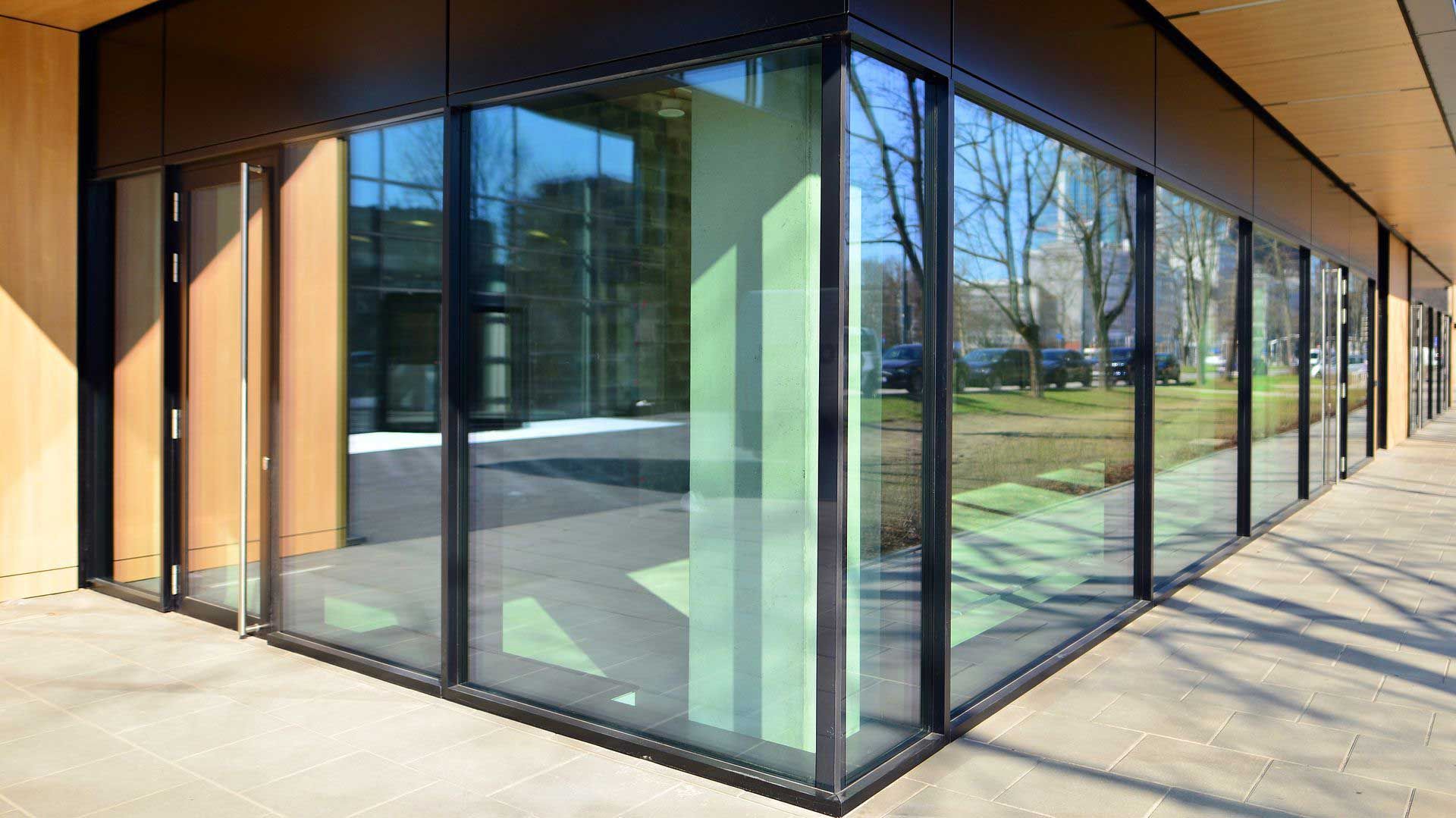 Modern building exterior with large glass windows reflecting the outdoors and a wooden facade.