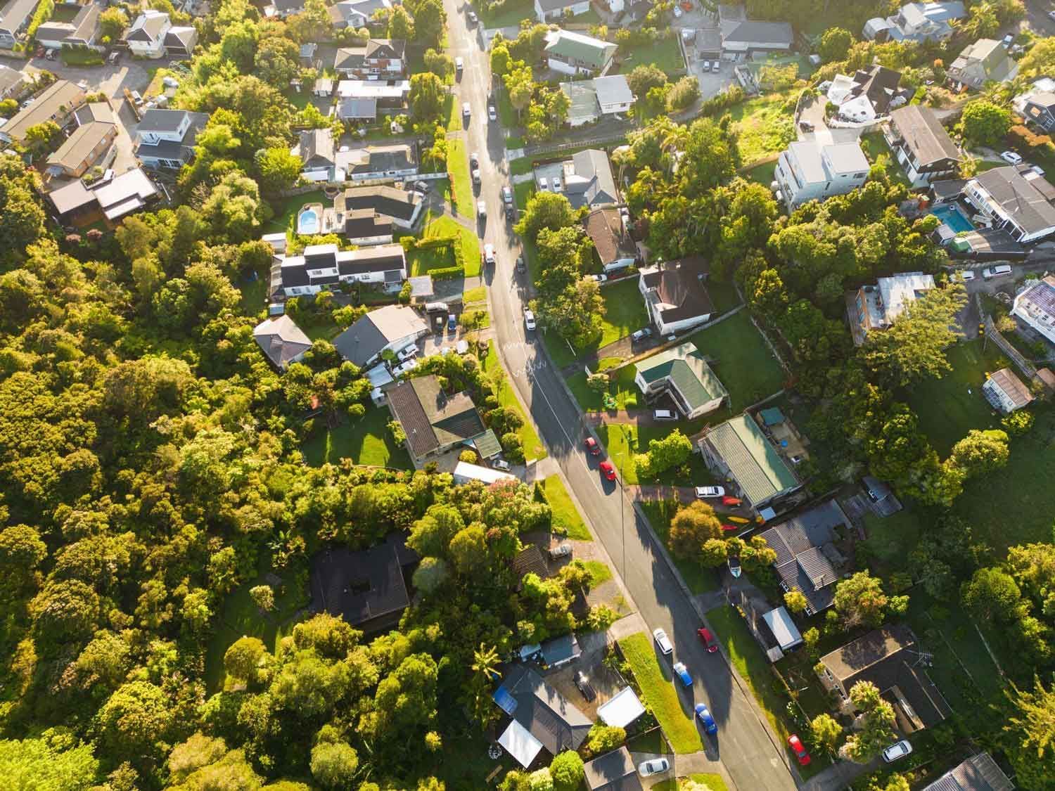 Aerial view of a residential area with houses, roads, and lush green trees. Sunny day. Aerial view of a residential area with houses, roads, and lush green trees. Sunny day.