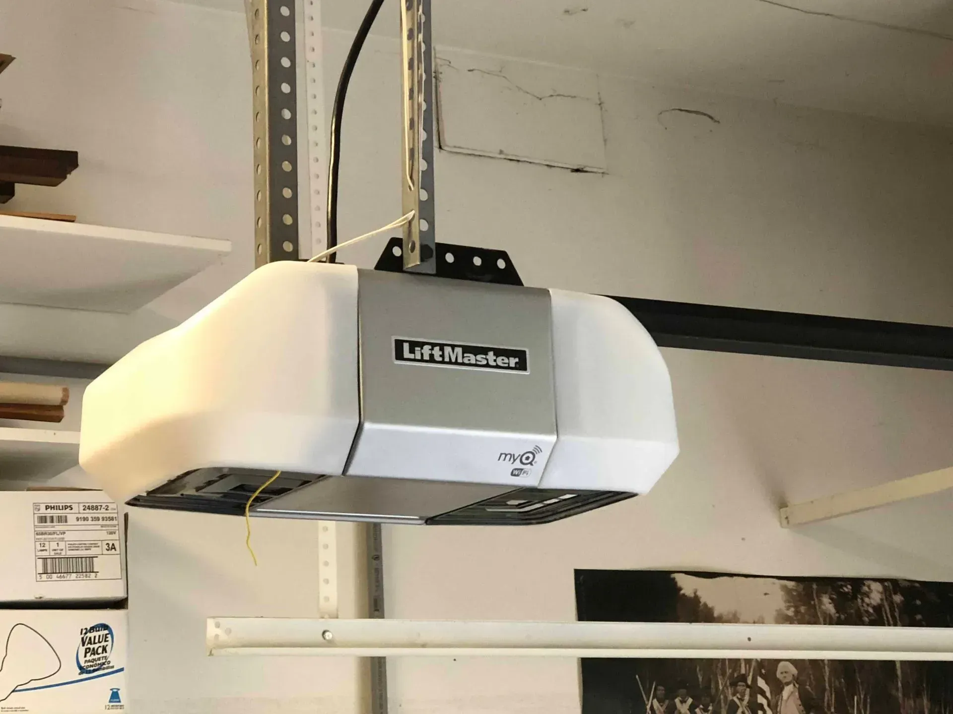 Garage door opener, white and silver, mounted on a track.