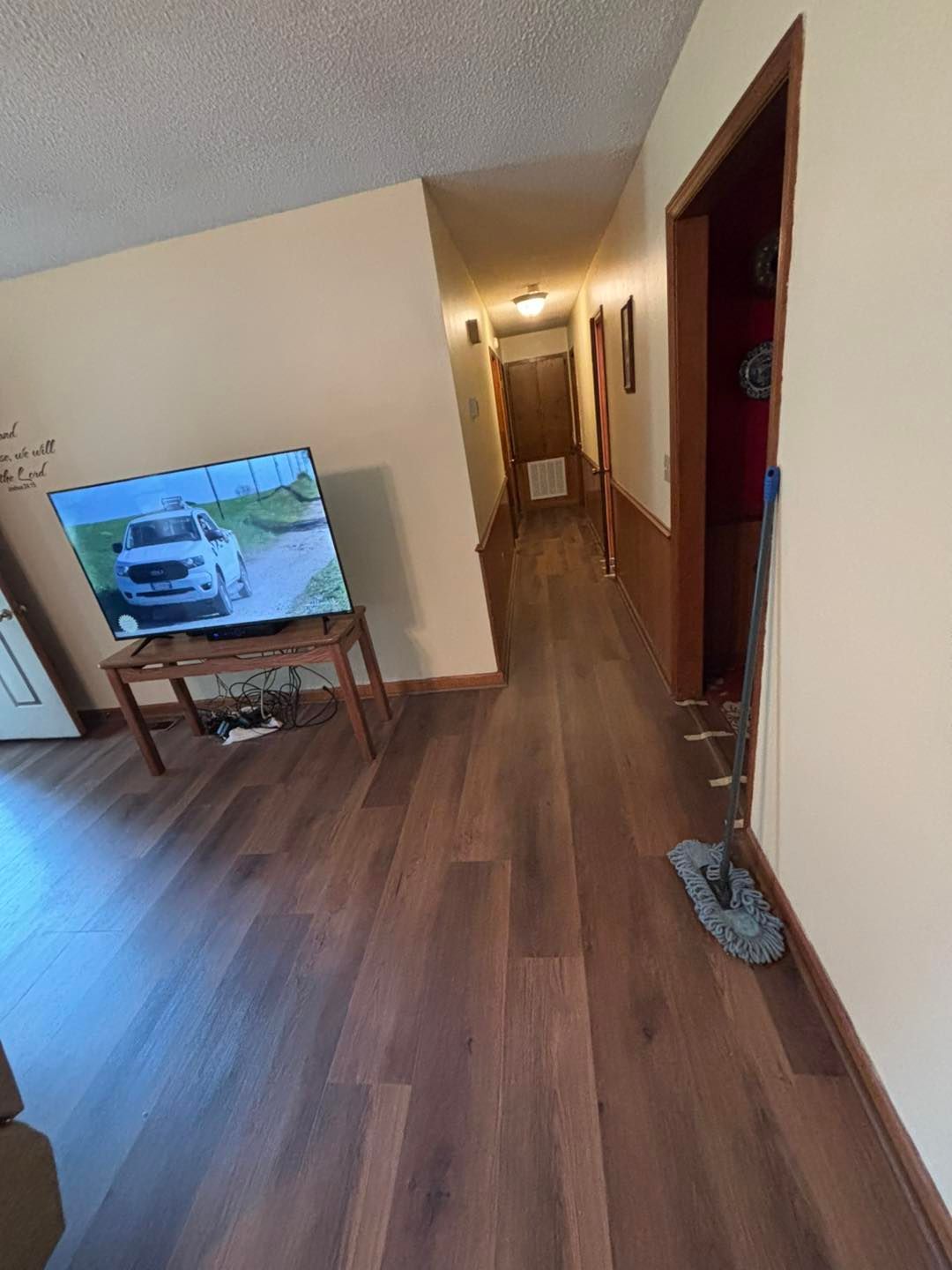 Hallway with wooden floors, leading to doors. A TV on a stand.