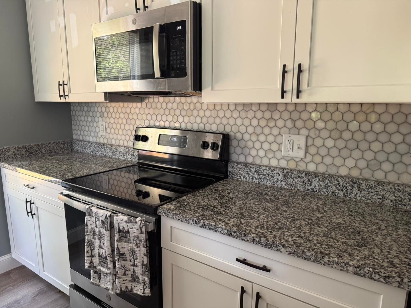 White kitchen cabinets, gray countertops, and stainless steel appliances.