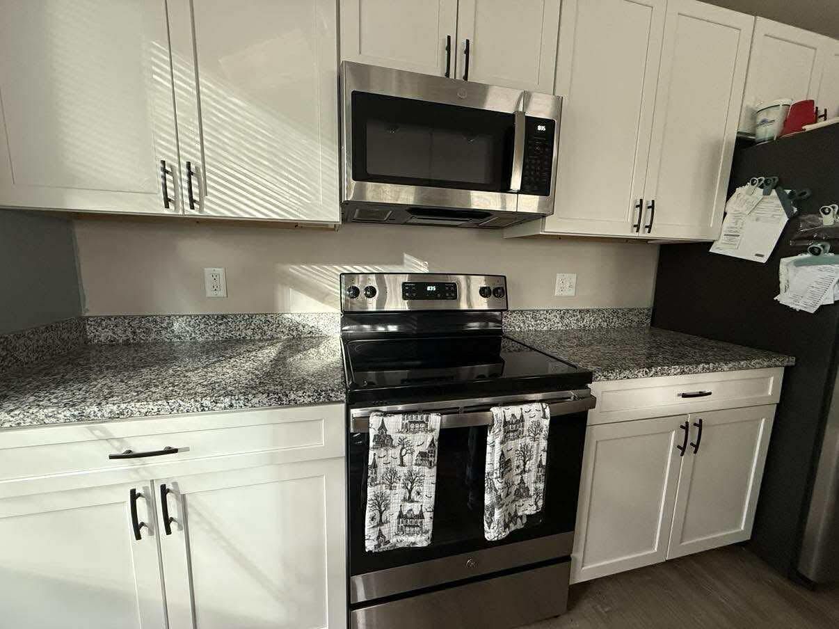 Kitchen with white cabinets, stainless steel appliances, and granite countertops.