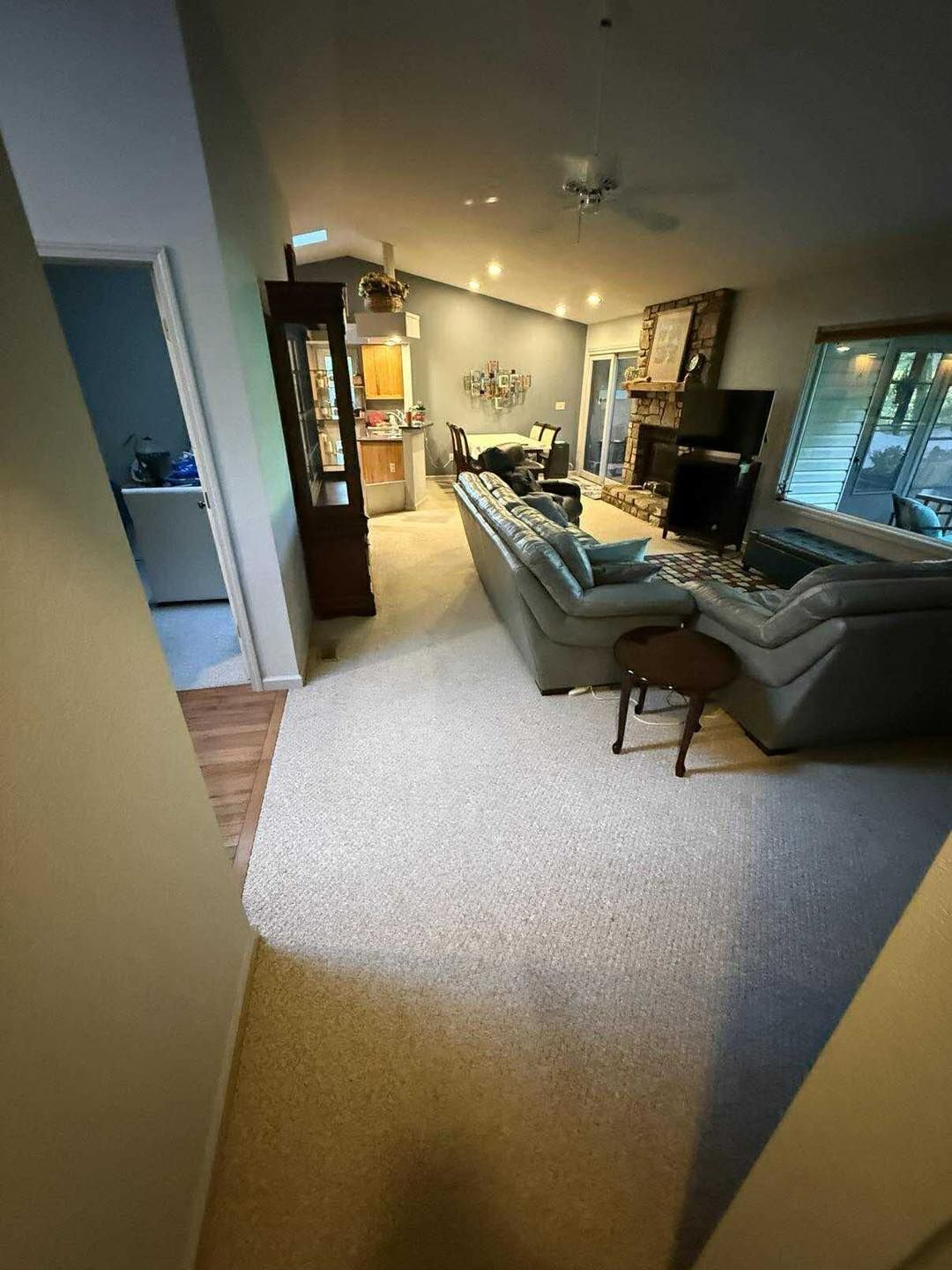 Living room with light-colored carpet, two sofas, a fireplace, and access to a kitchen area.
