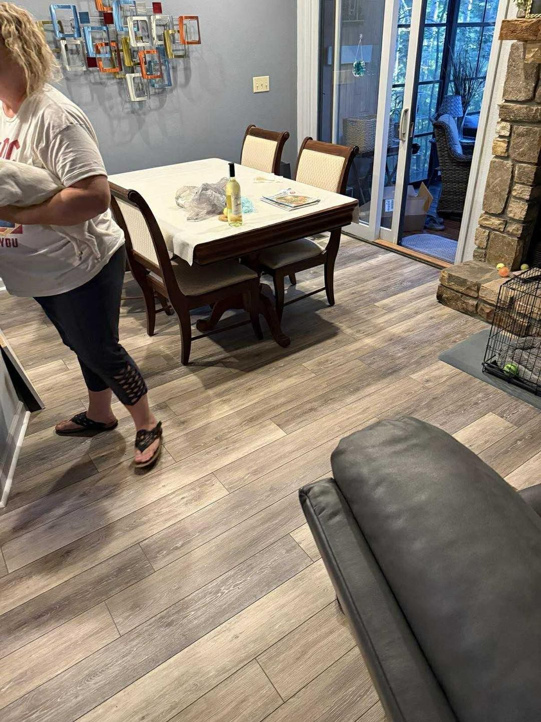 Woman stands near a dining table in a room with hardwood floors, a fireplace, and a sliding glass door.