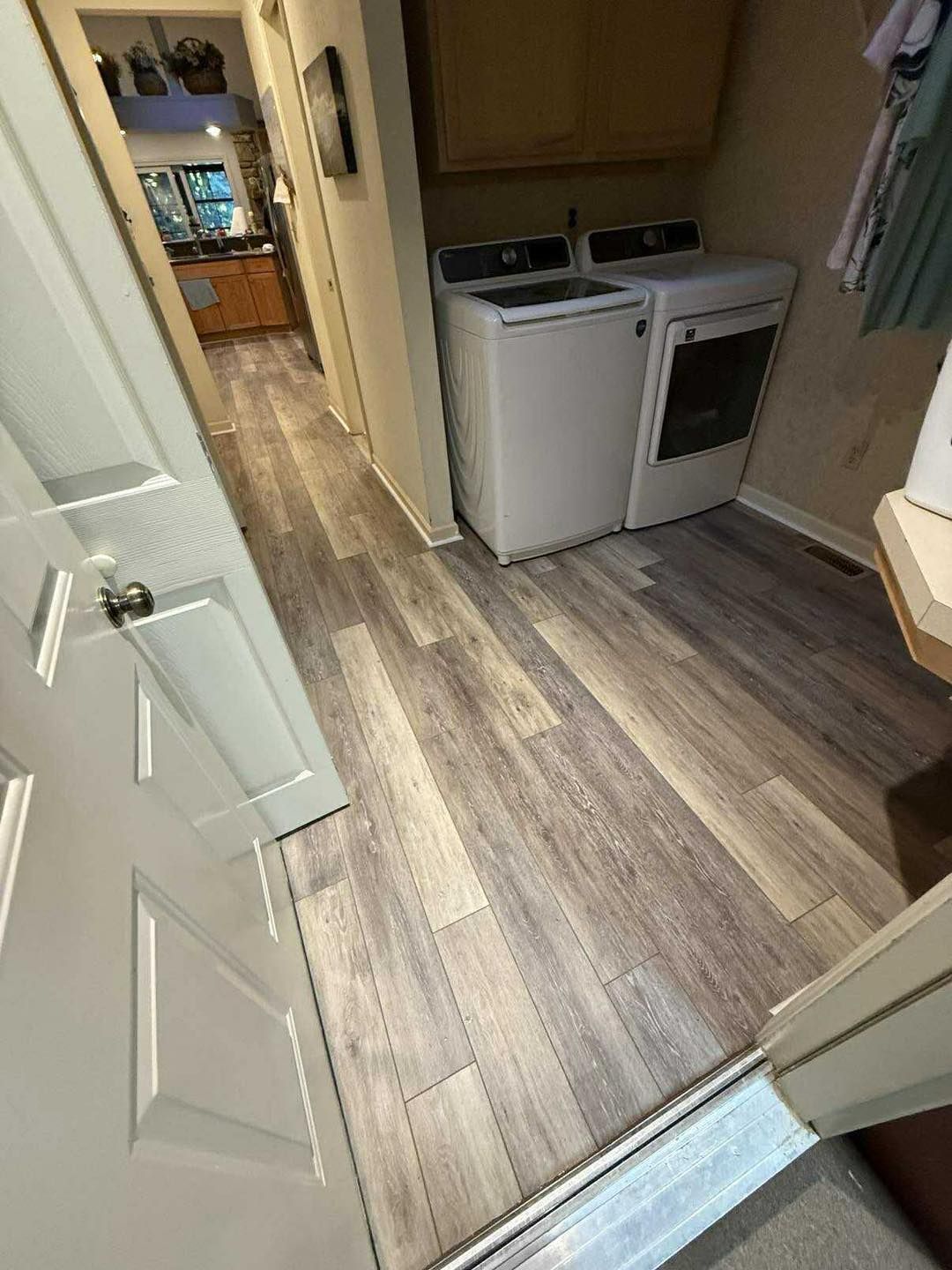 Hallway with wooden-look flooring, washer, and dryer.