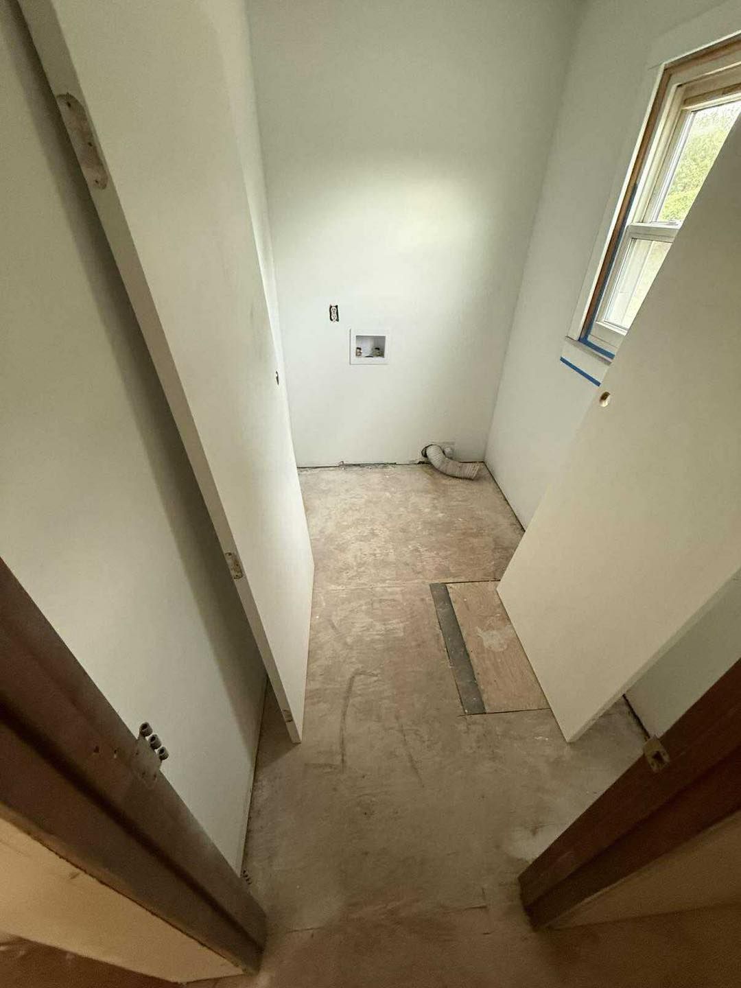 Empty laundry room with unfinished walls, flooring, and a window.