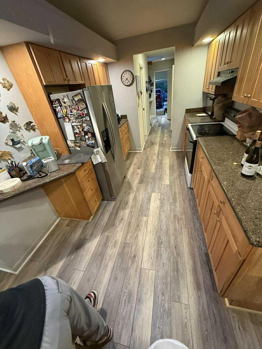 Kitchen with light wood cabinets, stainless steel refrigerator, and gray flooring.