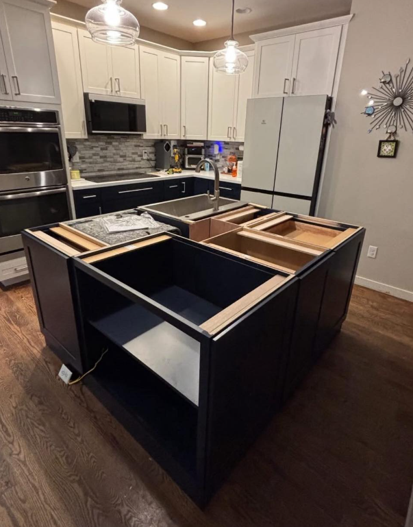 Wooden floor partially removed, revealing dark, damaged subfloor. Scattered wood planks nearby.