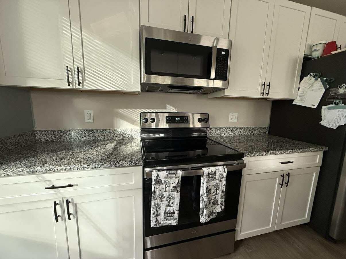 Kitchen with white cabinets, stainless steel appliances, and granite countertops.