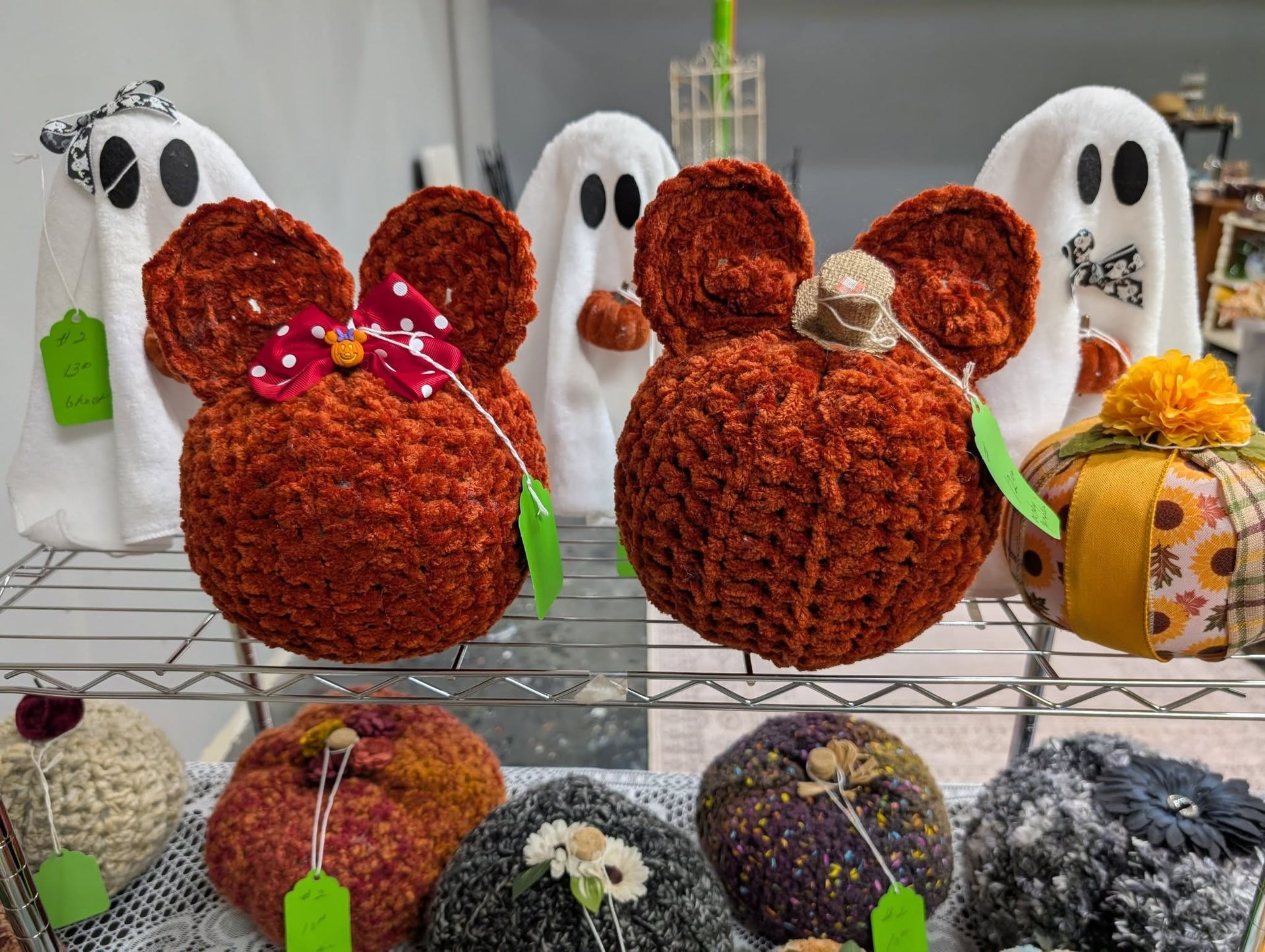 Crocheted pumpkin and mouse ears decorations, with ghost and other crafts on display.
