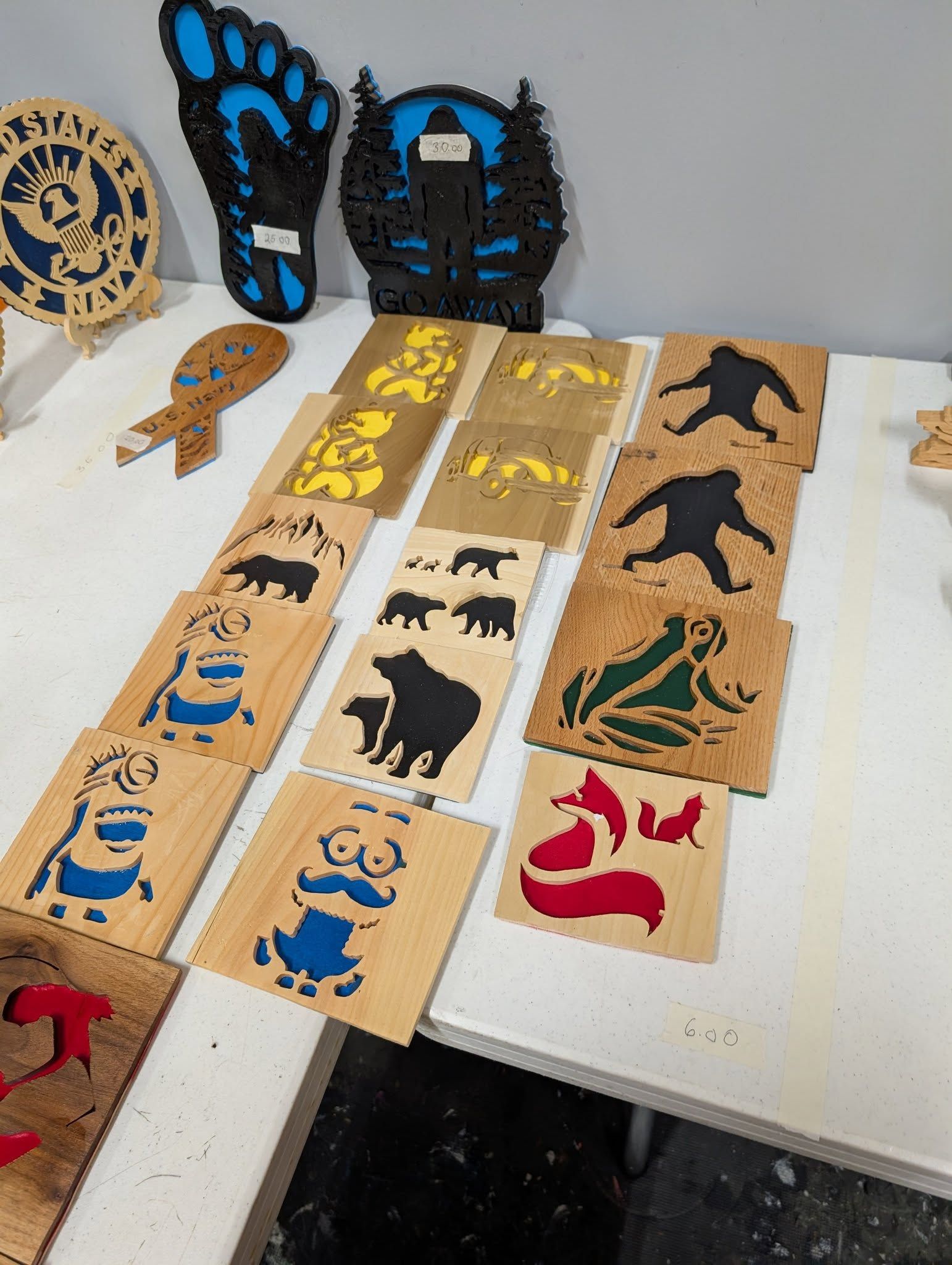 Wooden art pieces with animal and nature designs, in various colors, on a white table.