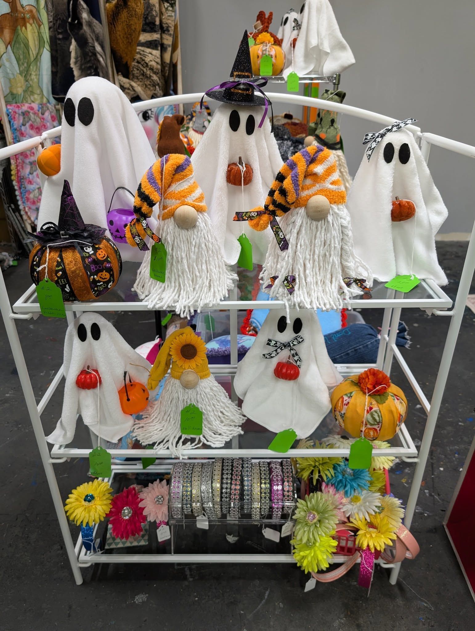 Halloween-themed crafts on white tiered shelf. Includes ghosts, pumpkins, and gnomes with colorful decorations.