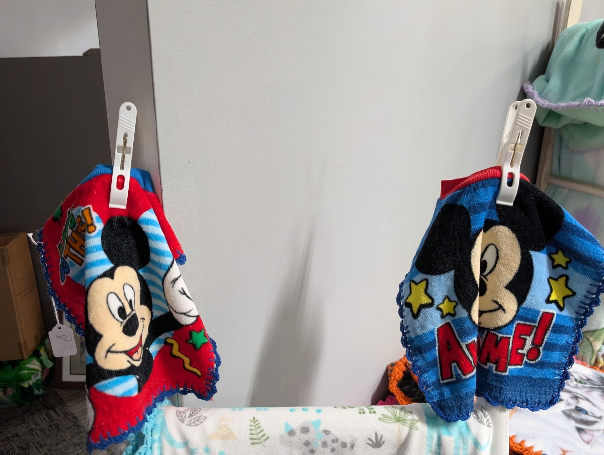 Two Mickey Mouse washcloths hanging on a line, one red and one blue.