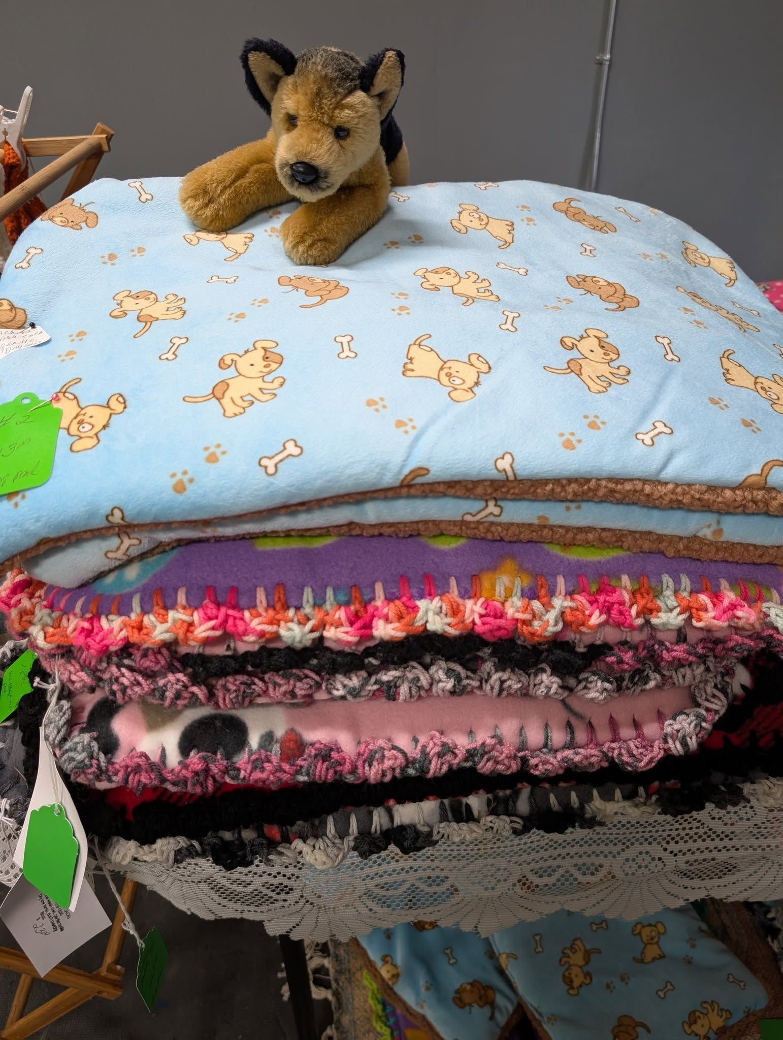 Stack of pet beds, with toy dog on top, various colors and patterns.