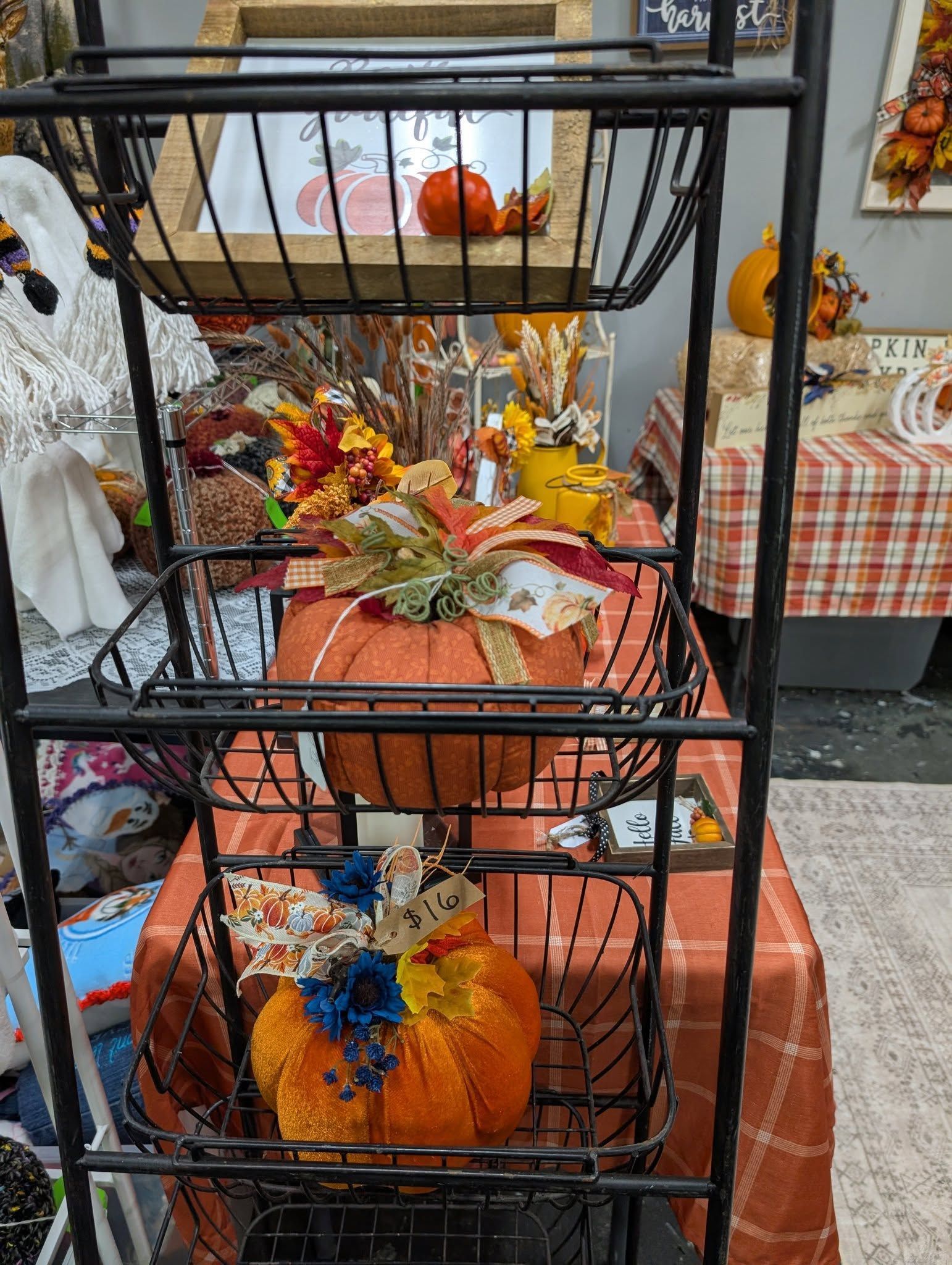 Black tiered metal shelf with decorative pumpkins and fall foliage.