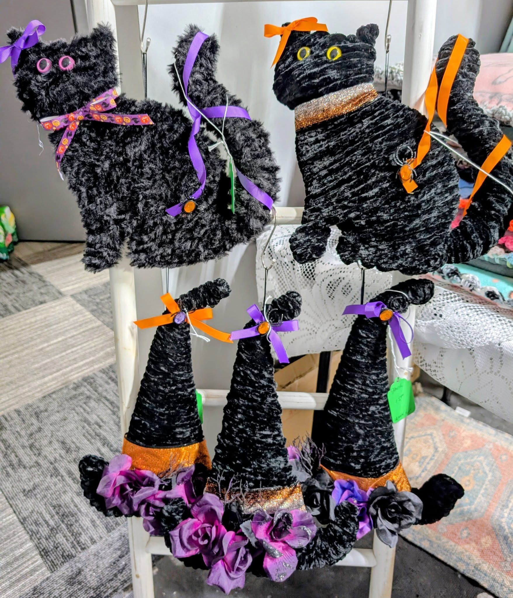 Halloween decorations: black cats and witch hats made of yarn, on a white chair.