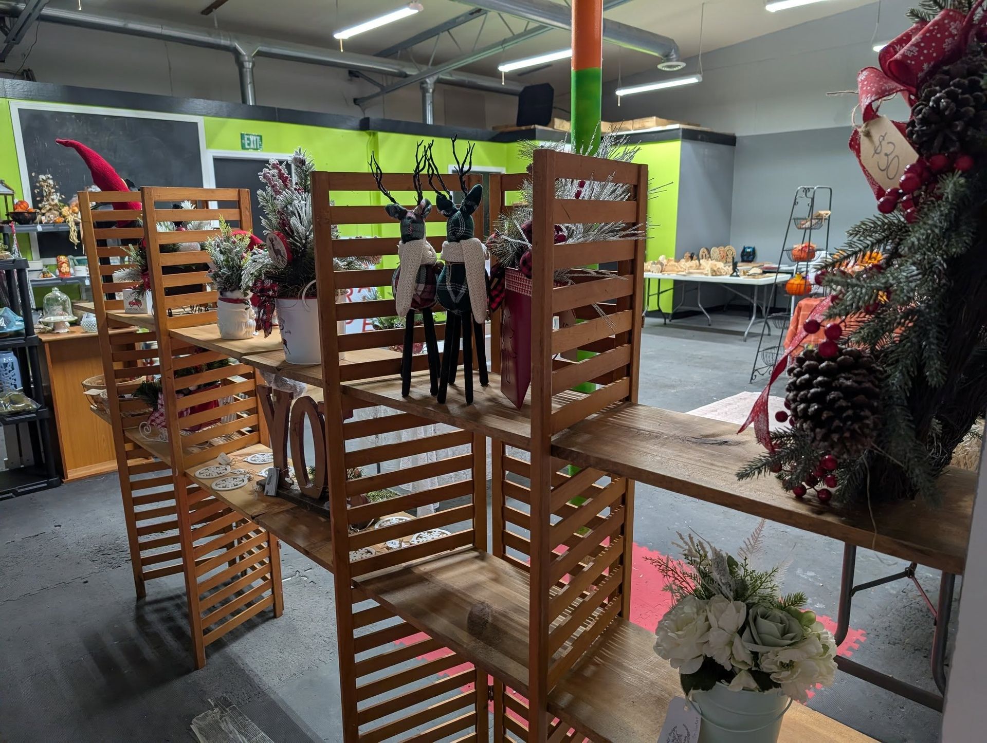 Wooden display shelves in a shop, showcasing decorative items including deer figurines and floral arrangements.