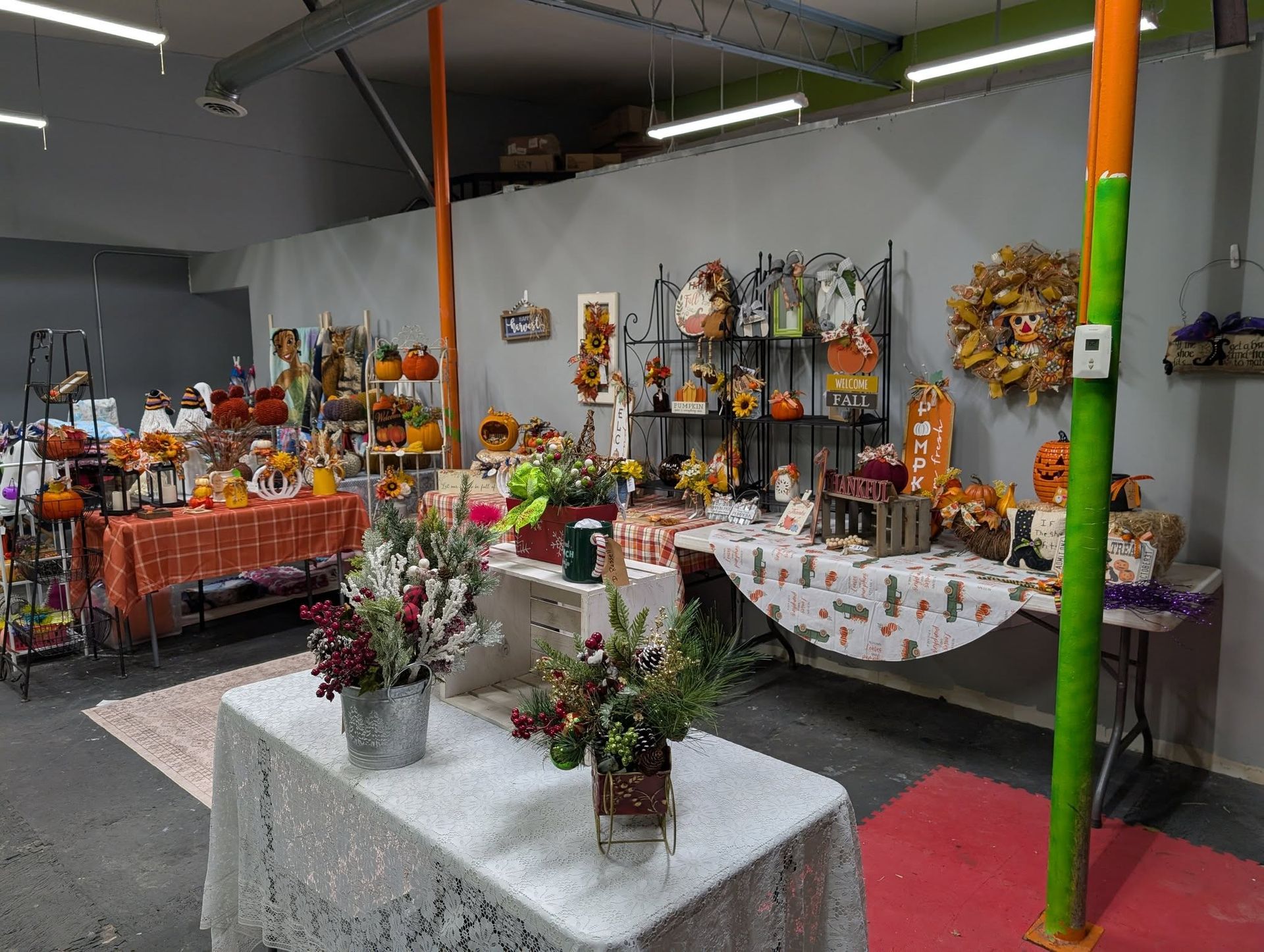 Interior shop display of fall decorations, pumpkins, wreaths, and floral arrangements.