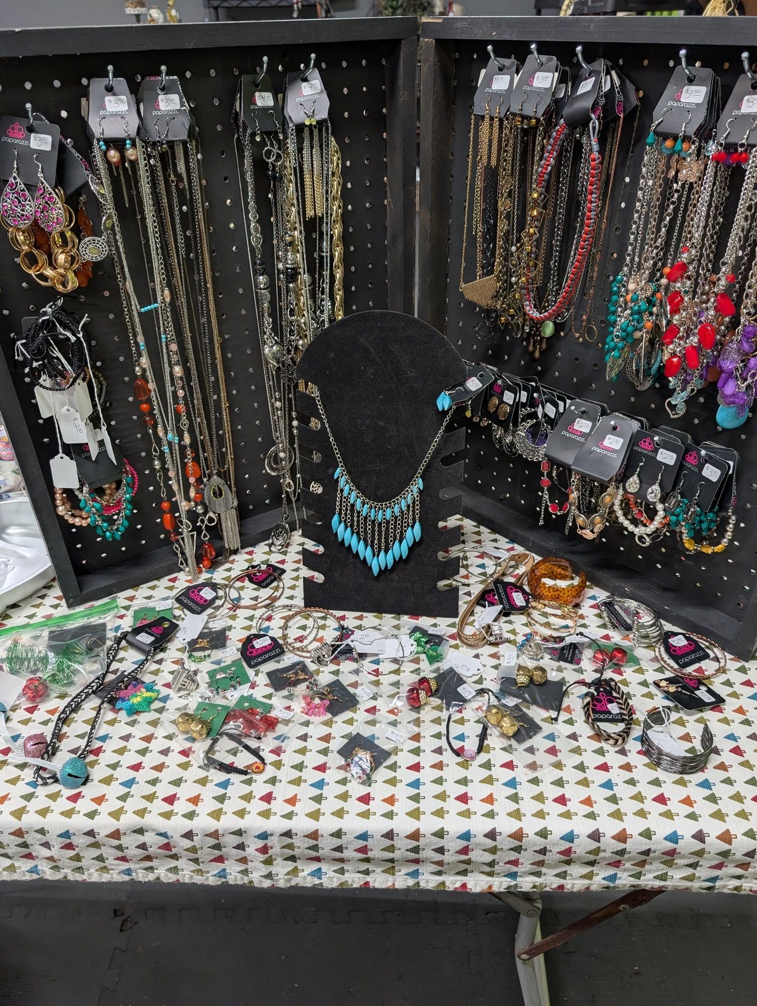 Jewelry display at a vendor booth. Necklaces and earrings on black stands and table with heart pattern.