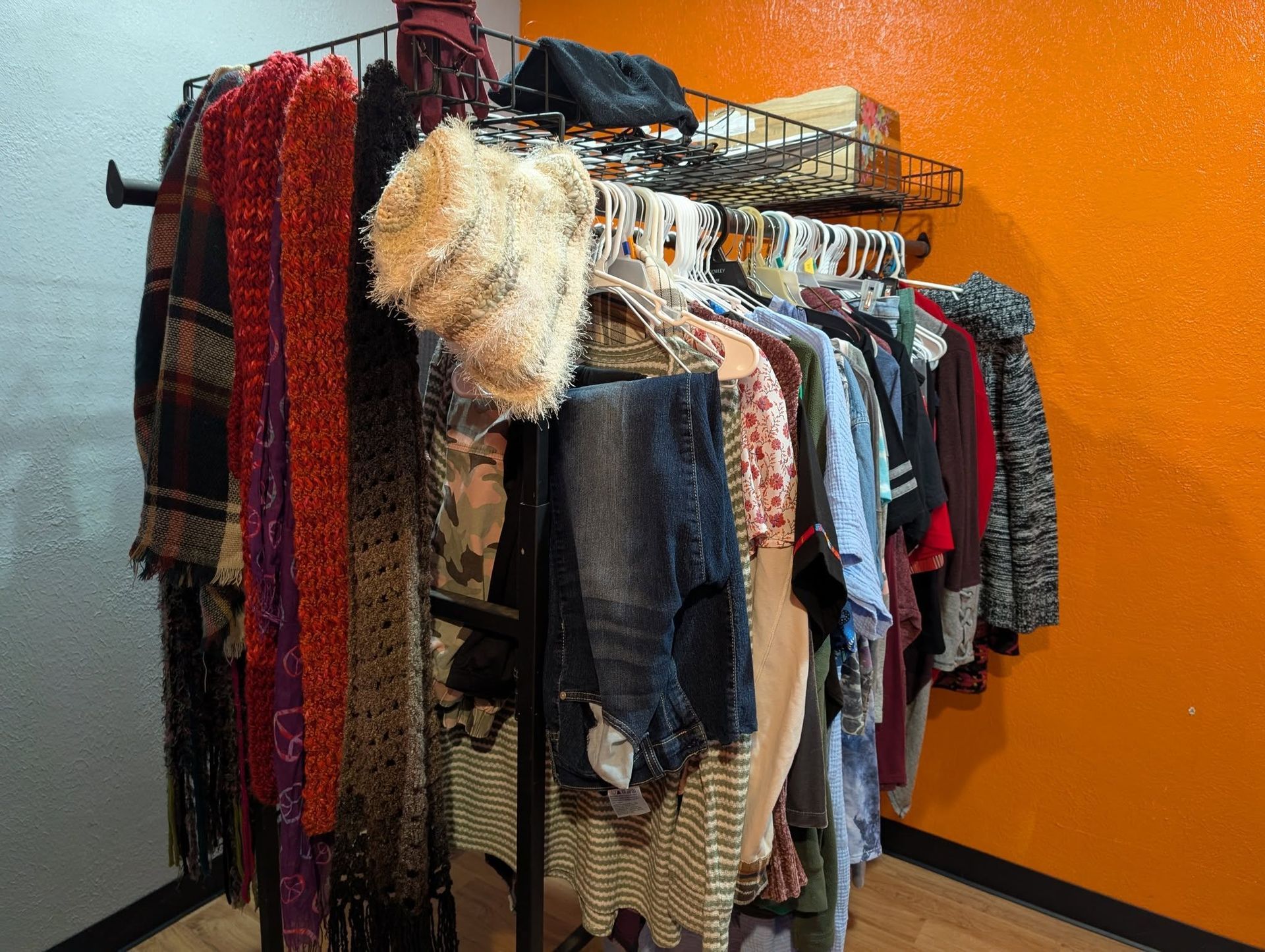 Clothing rack with various garments displayed; orange and gray walls.