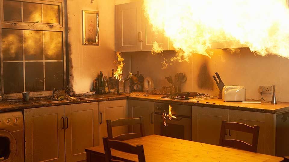 A kitchen with a fire coming out of the stove.
